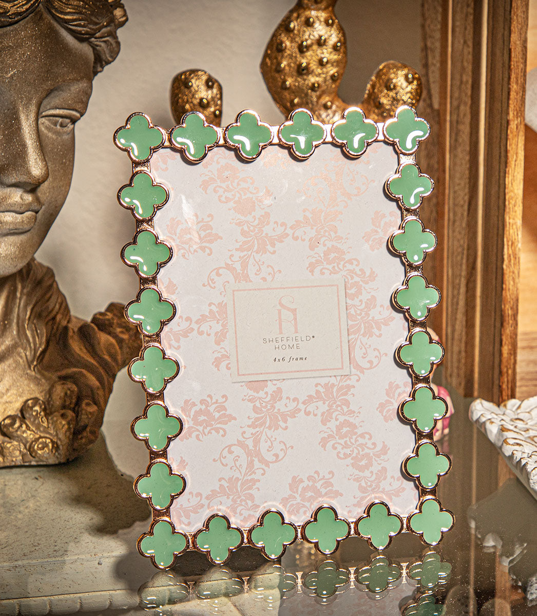 Decorative photo frame with green clover patterns on a surface.