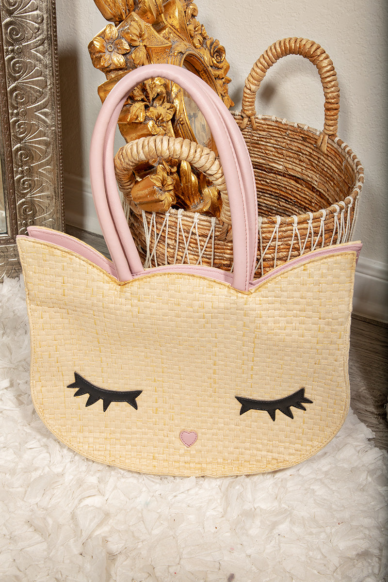 Woven cat-shaped basket with pink accents and a gold decorative object in the background.