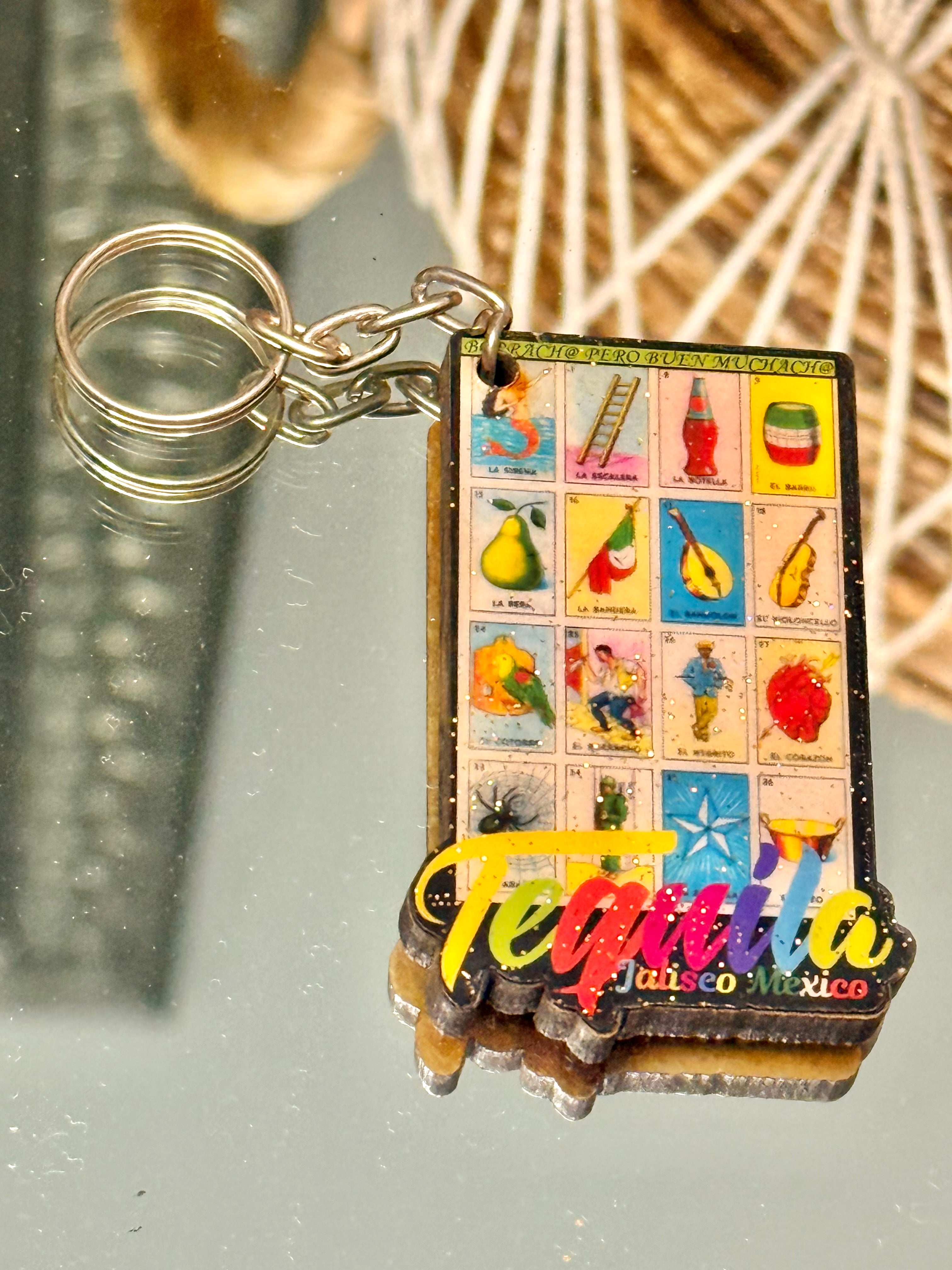 Keychain with colorful design and 'Tequila Jalisco Mexico' text on a reflective glitter loteria print surface.