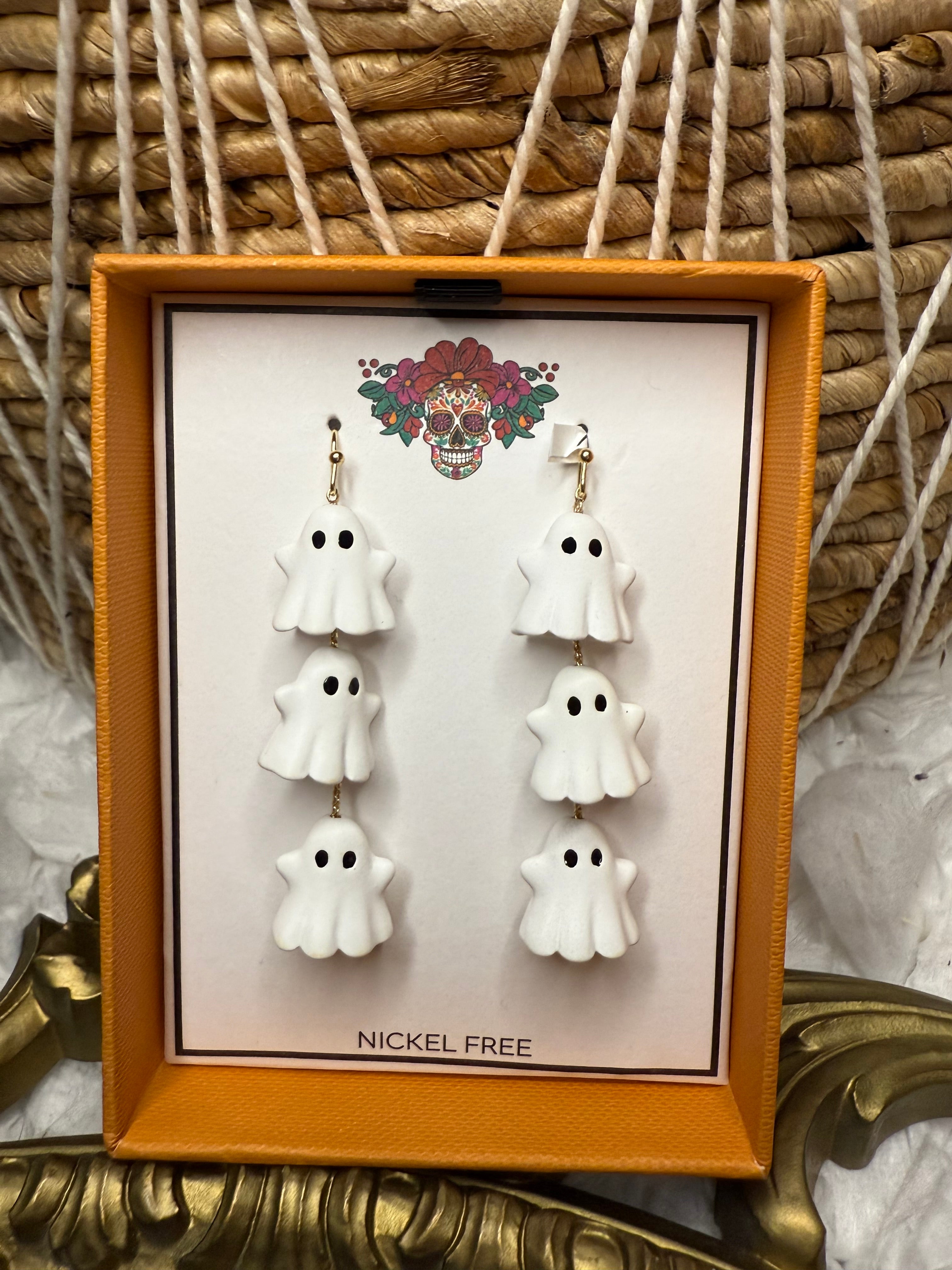 Set of white ghost earrings in a decorative box with a brand logo.