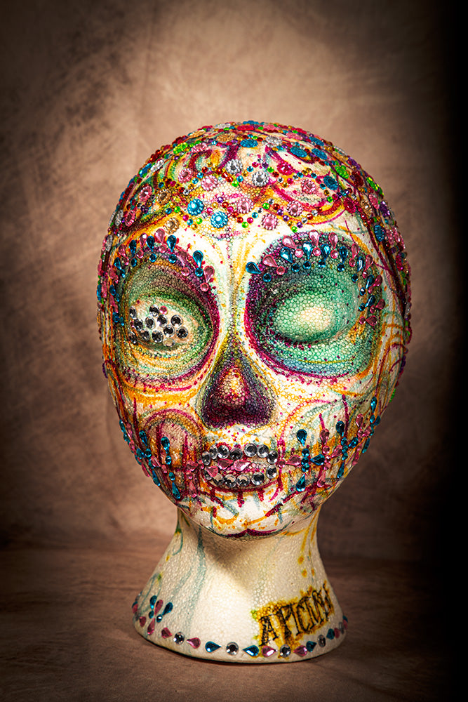 Handmade rhinestone sugar skull art head with colorful stones and intricate Mexican folk design.