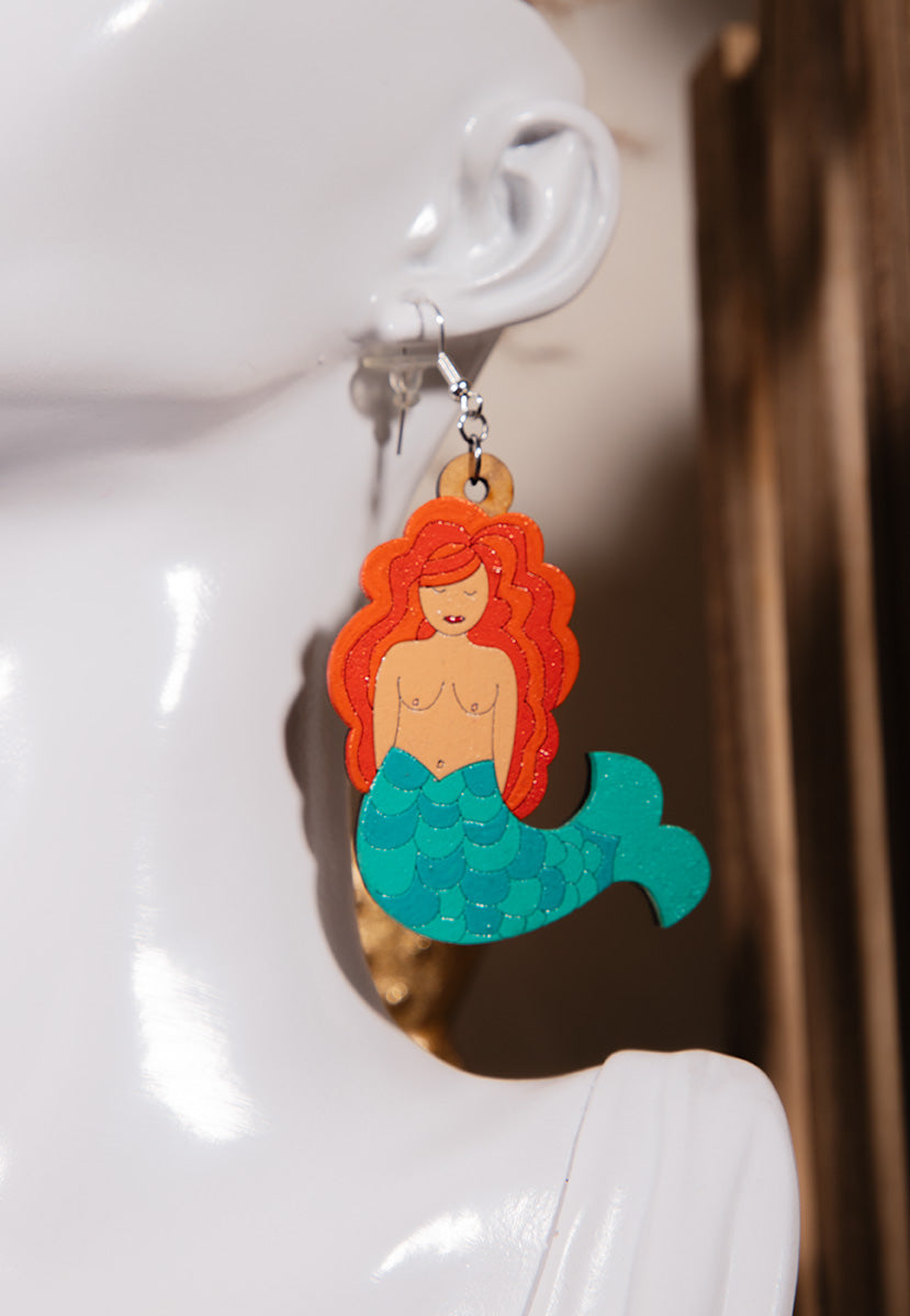 laser cut wood earrings shaped as mermaids with red hair and green tail ocean fantasy jewelry