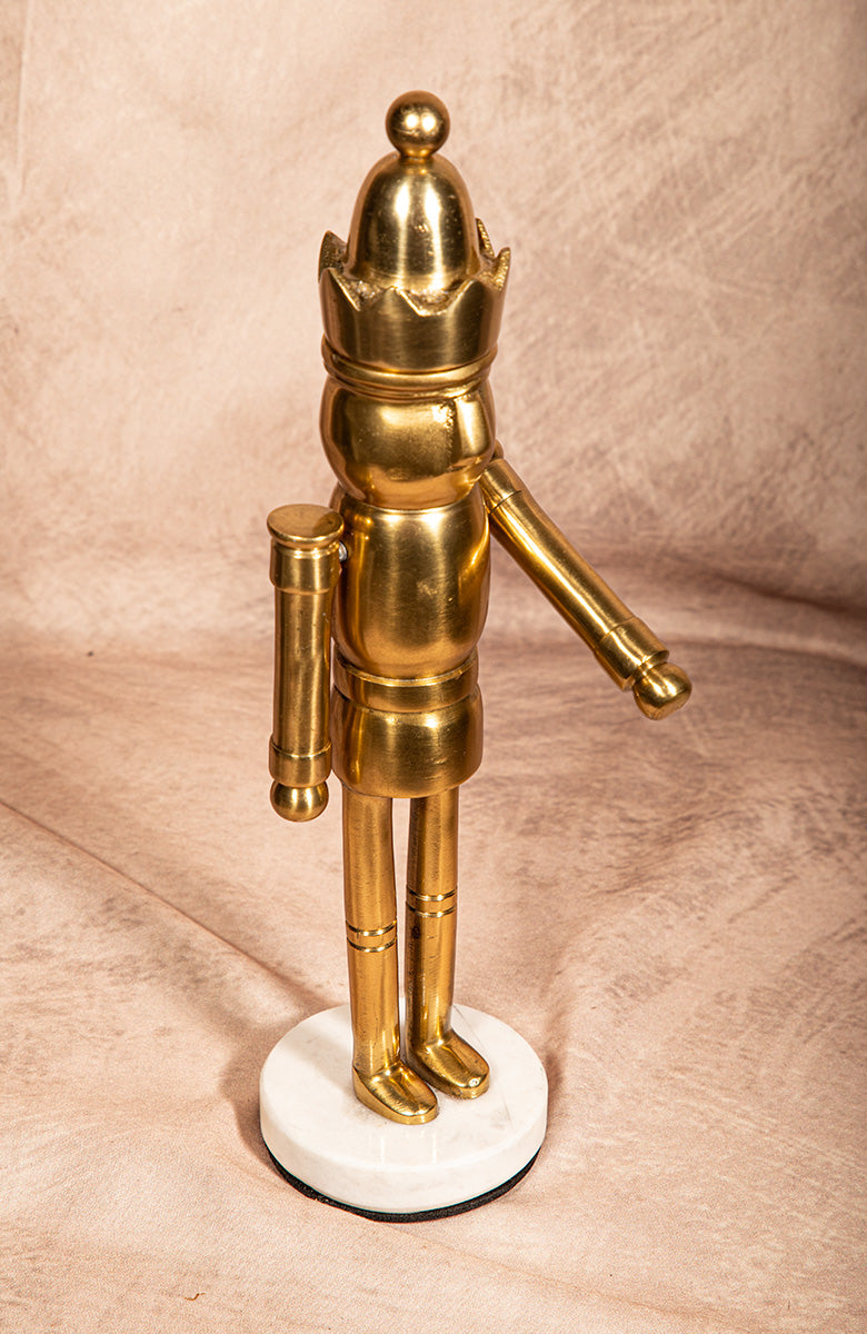 Side view of a small golden Bauhaus chess king figurine on ivory base — modern brass sculpture with one moveable arm, minimalist décor accent.