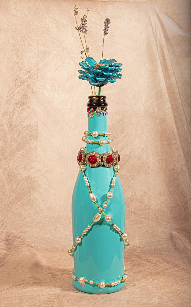 Repurposed blue wine bottle with pearls, shells, and ocean mermaid accents.