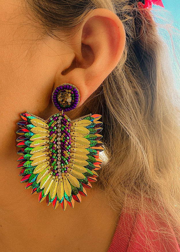Alive with color and movement, these Mardi Gras-inspired earrings feature shimmering feathers outlined by tiny iridescent beads. Their vibrant green, gold, and violet tones echo parade lights and music, while their lightweight structure adds effortless drama. Perfect for festival looks or everyday confidence.