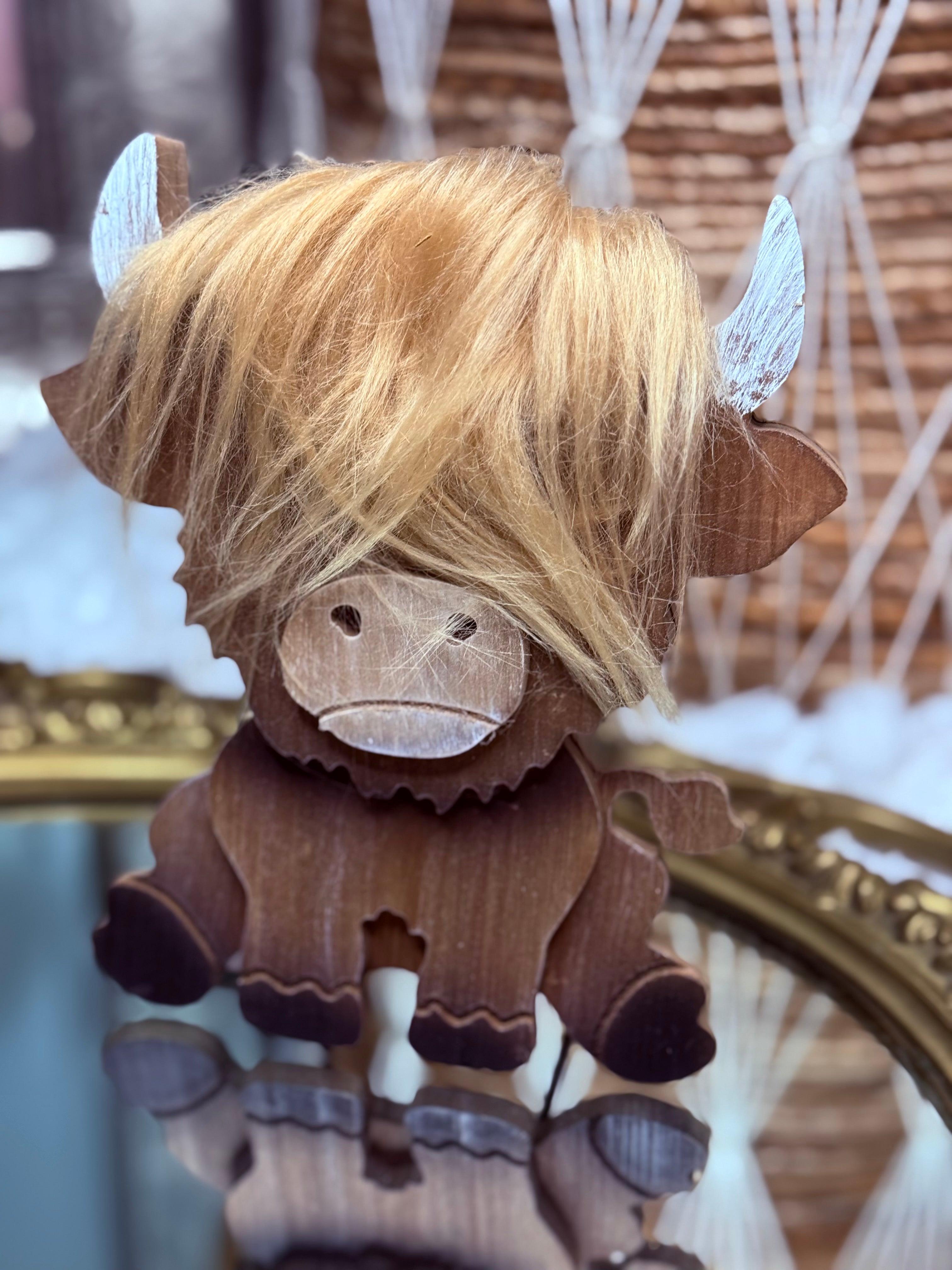 Wooden western highland cow with blonde hair on a reflective surface