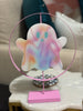 Colorful ghost-shaped decoration on a stand with a pink circular frame.