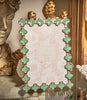 Decorative photo frame with green clover patterns on a surface. 
