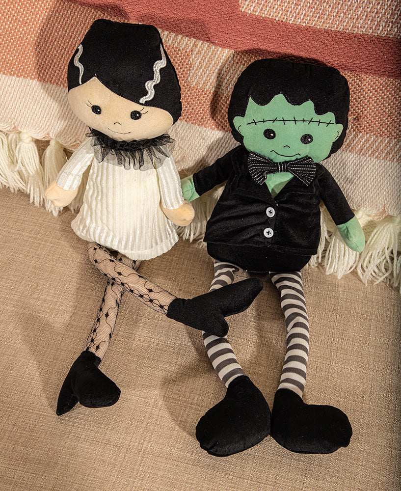 Two plush dolls resembling a couple on a textured surface