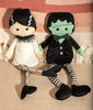 Two plush dolls resembling a bride and groom on a textured fabric background