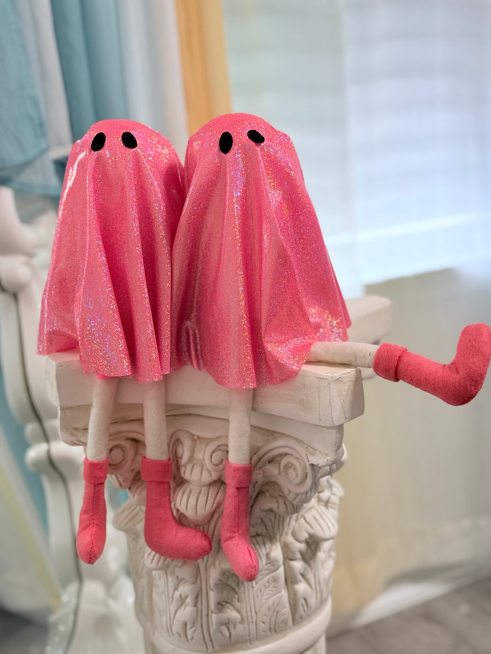Two pink Rave ghost-shaped plush toys on a decorative column.