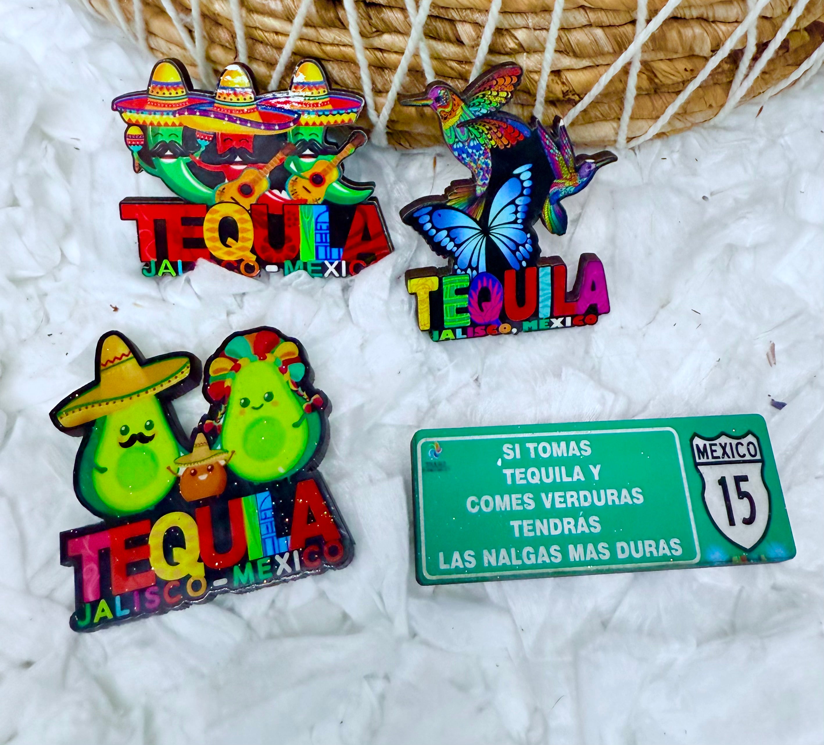 Colorful tequila-themed pins with a humorous Mexican road sign on a textured white background.