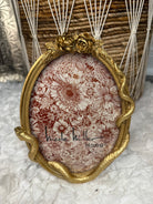 Decorative picture frame with floral and snake design and gold frame on a textured surface