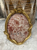 Decorative picture frame with floral and snake design and gold frame on a textured surface