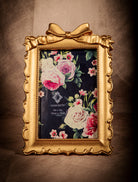 Antique gold picture frame with ribbon bow detail, vintage Hollywood Regency decor.