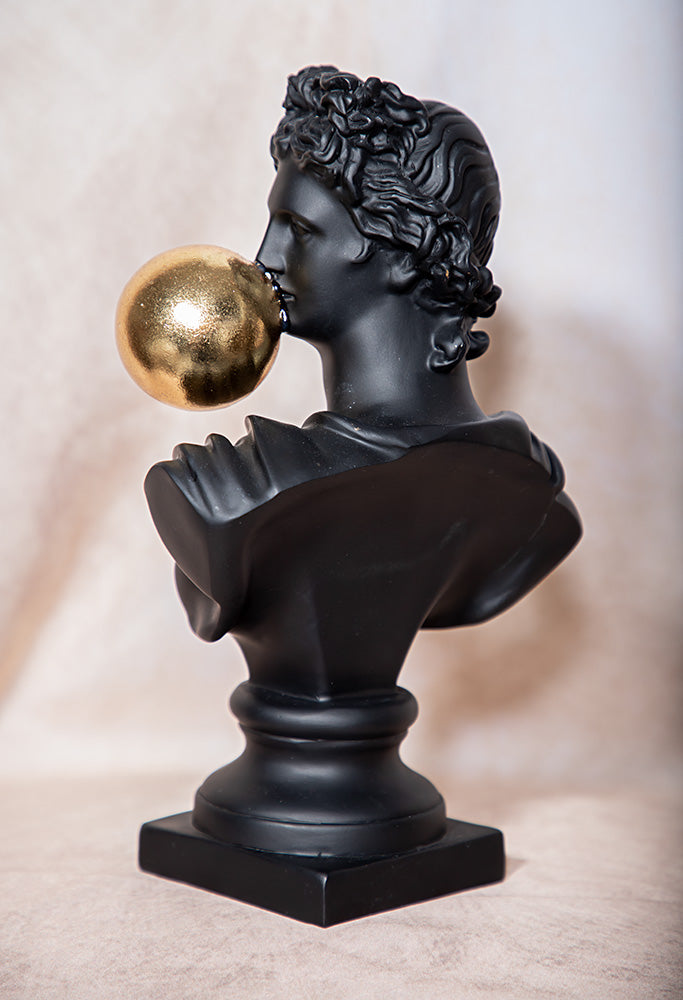 Bust of a classical figure with a gold ball on a beige background