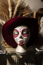 Hand-painted sugar skull art head featuring floral details, Mexican folk colors, and gothic Halloween style.