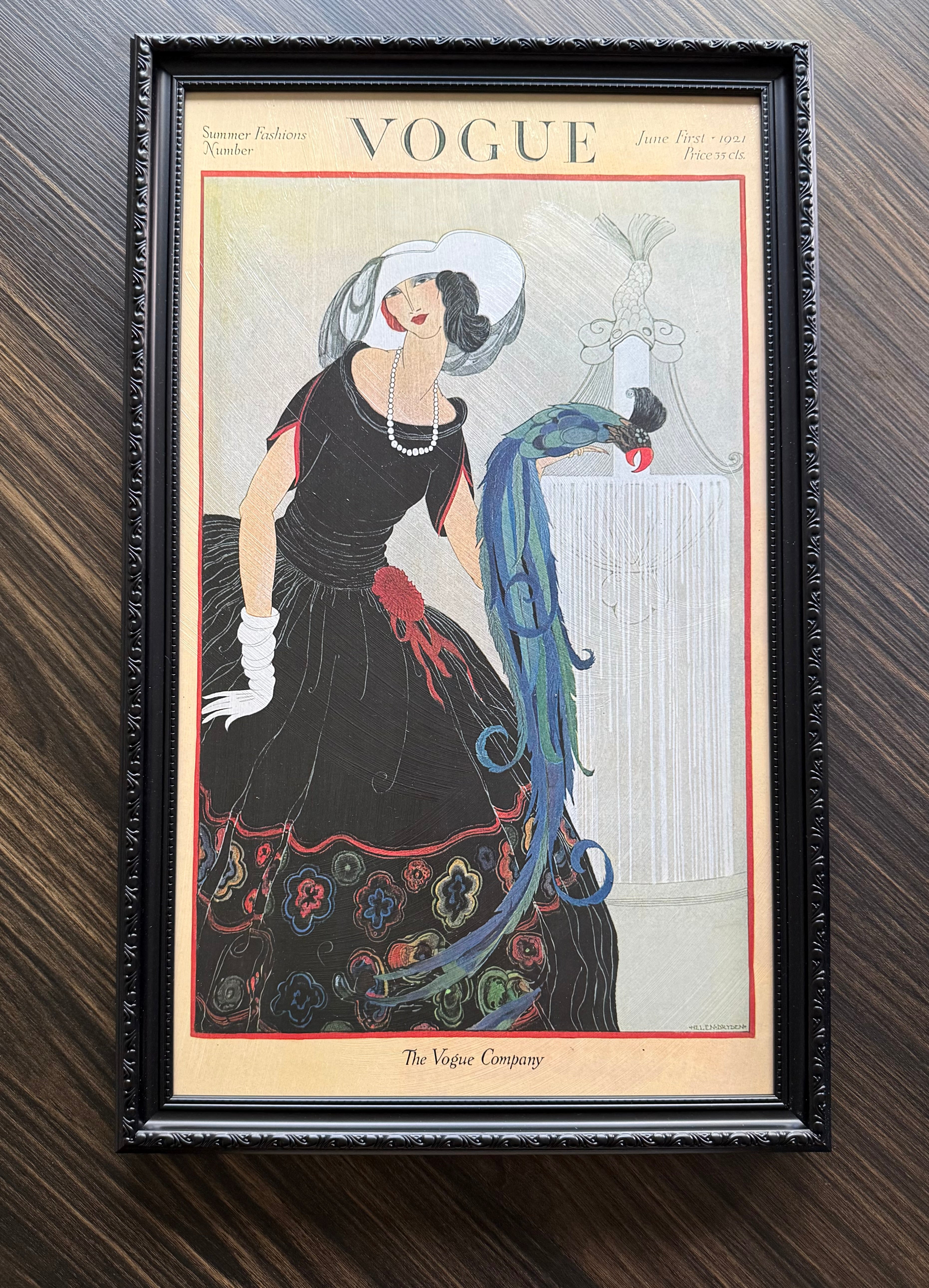 Framed Vogue Summer Fashions 1921 cover art with woman in black dress, pearls, and blue peacock in sleek black frame wall décor.