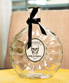 A clear glass arsenic bottle with a black skull-shaped cap and a label that reads 'Resinic - Slow & Painful'.
