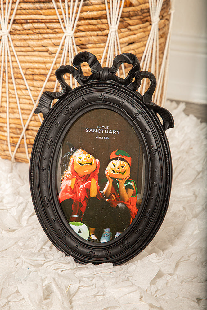 Gothic black oval picture frame with bow and ribbon detail, perfect for vintage or Halloween wall decor.
