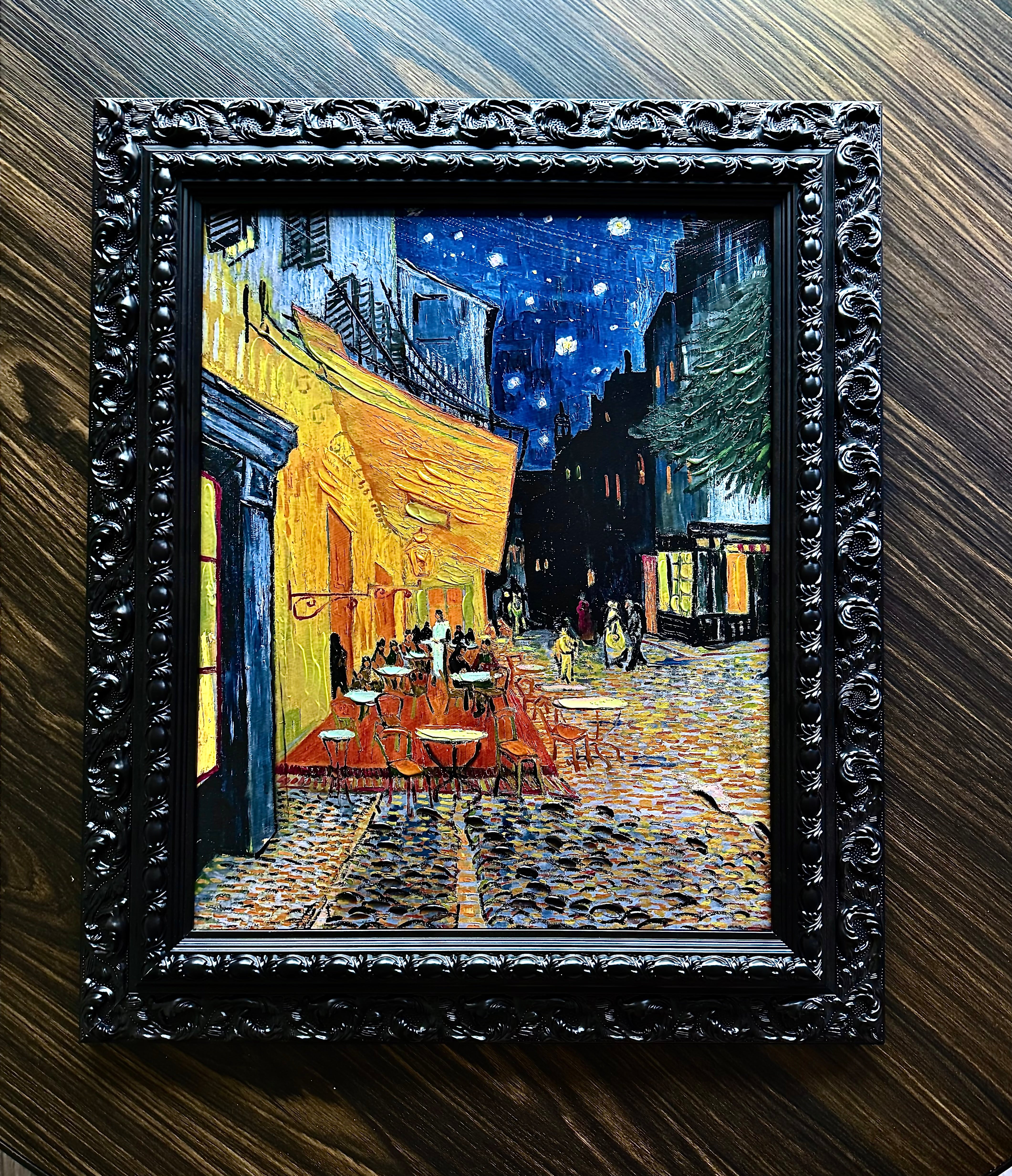Ornate black baroque frame featuring textured Van Gogh Café Terrace at Night canvas art on dark wood background.