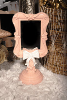Pink and white bow vanity mirror in Rococo style, shabby chic decor for romantic bedrooms or dressing areas.
