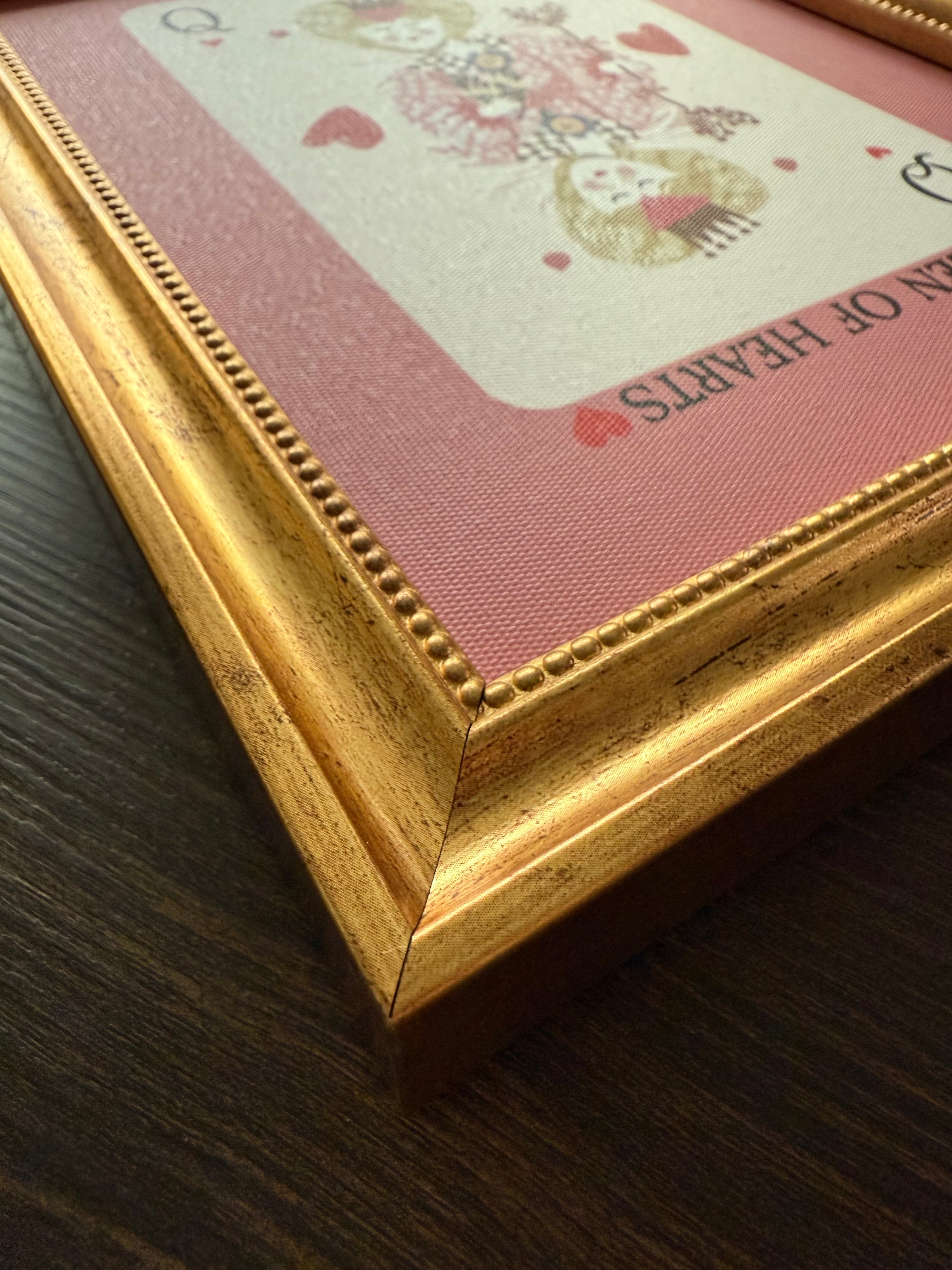 Framed card with 'Queen of Hearts' design on a wooden surface