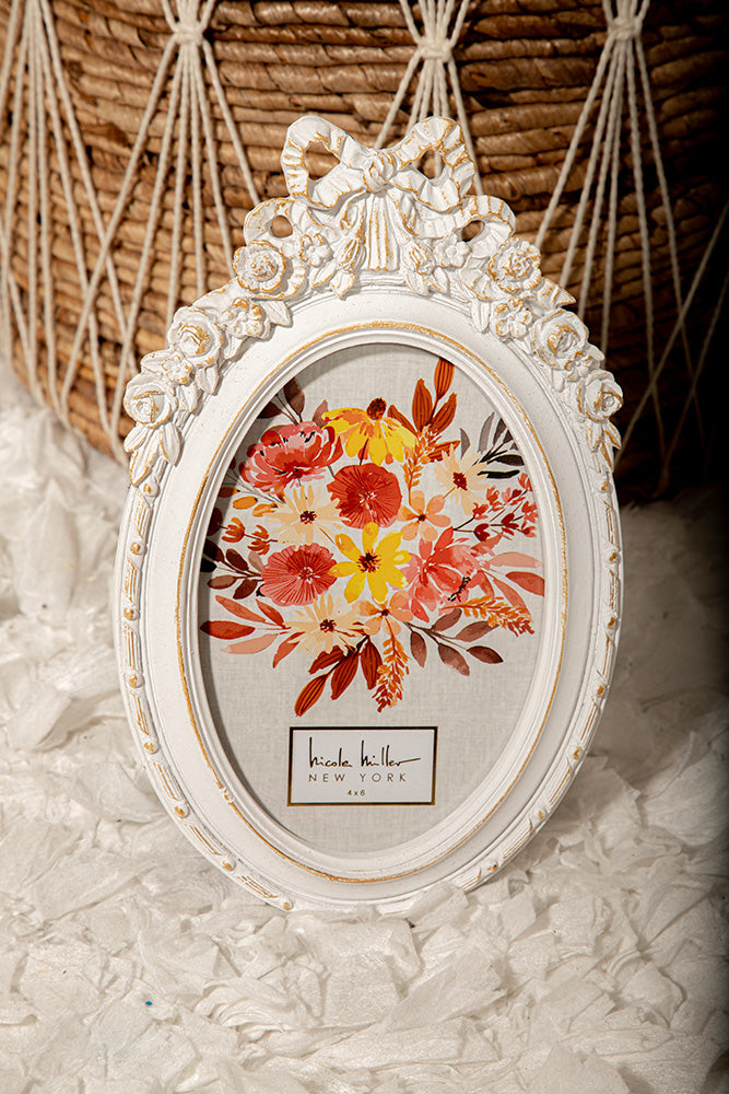 Shabby chic oval white picture frame with floral bow, ideal for vintage photo or home decor.
