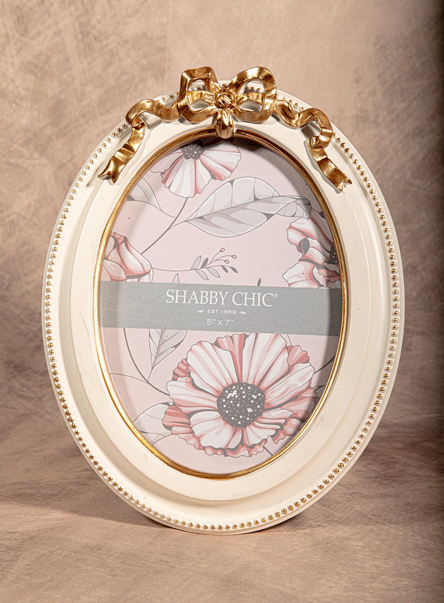 White and gold oval picture frame with bow detail, shabby chic vintage decor.