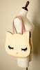 A beige straw toe handbag with a cat design, featuring button closure and a mannequin display. Hello Kitty inspired bag.